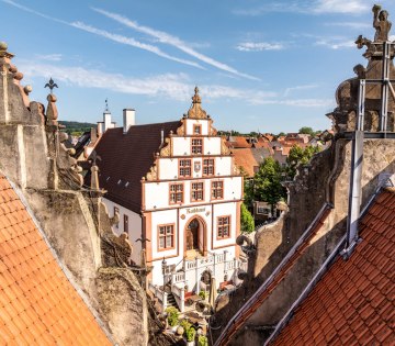 Das historische Rathaus als Drohnenaufnahme zwischen zwei gegenüberliegenden Schmuckgiebeln hindurch fotografiert