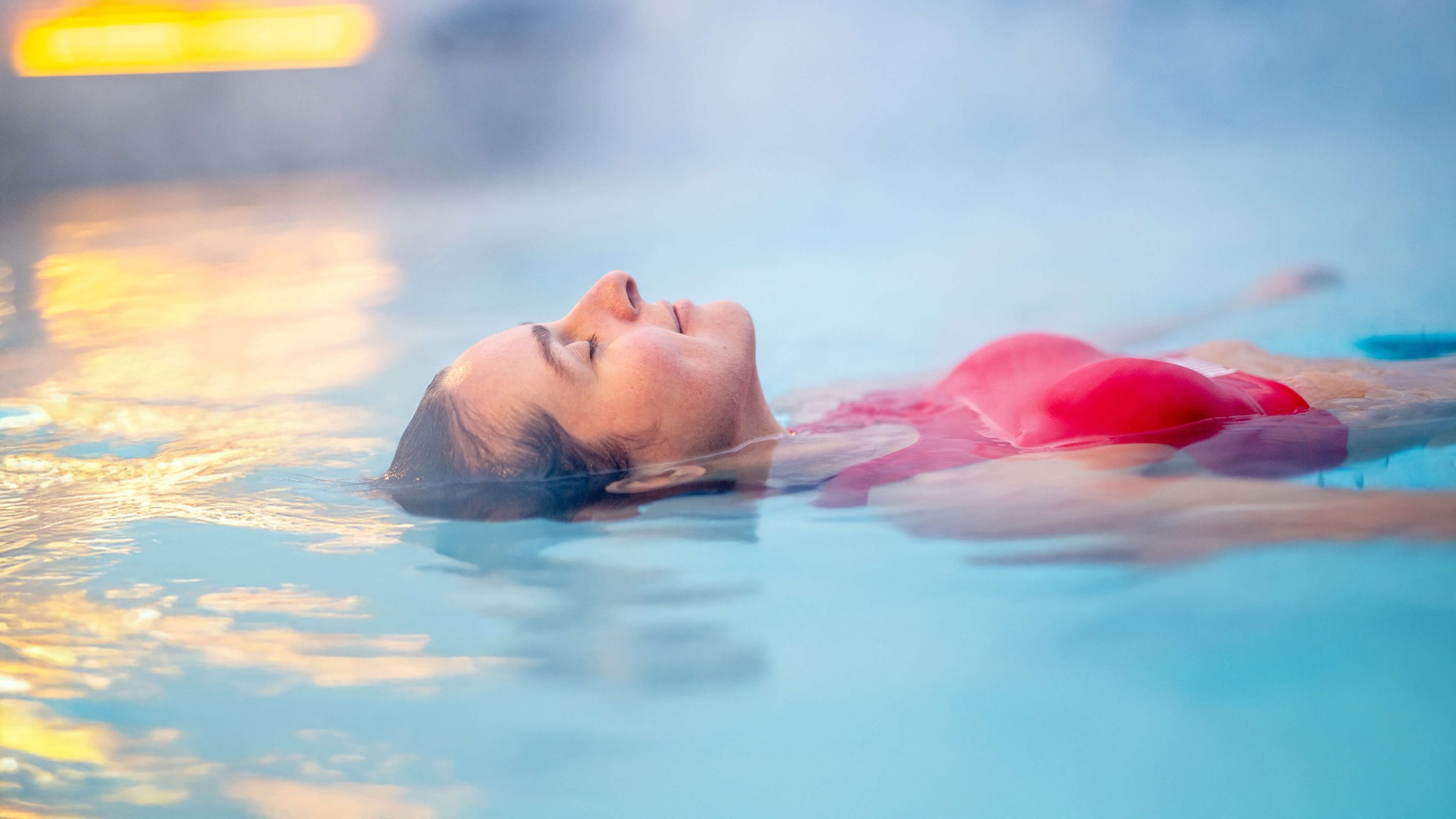 Frau liegt schwebend auf der Wasseroberfläche in einem Außenbecken der Vitasol-Therme