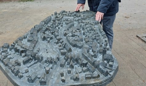 Bildhauer Egbert Broerken aus Soest am neuen Zinnbronze-
Tastmodell im Maßstab 1:500, aufgestellt in der Parkstraße auf Höhe des Hauses Nummer sechs, mit dem sich
die Innenstadt von Bad Salzuflen erfühlen lässt, © Stadt Bad Salzuflen