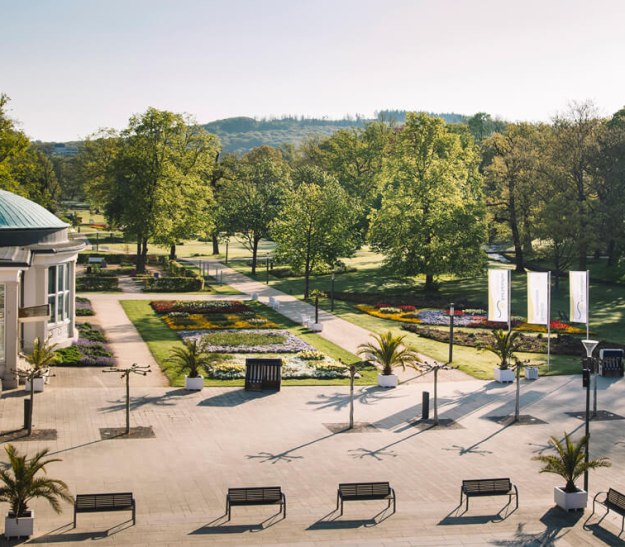 Man sieht den gepflasterten Bereich des Kurparks zwischen Konzerthalle und Kurhaus, sowie die ersten Rasenflächen und Beete