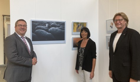 Axel Lehmann, Landrat des Kreises Lippe, Beate Hoffmann-Hildebrand, stellvertretende Bürgermeisterin der Stadt Bad Salzuflen, und Günter Weigel, Geschäftsführer Tourismus &amp; Marketing Lippe GmbH, stehen vor einem Bild der neuen Ausstellung in der Wandelhalle, © Stadt Bad Salzuflen